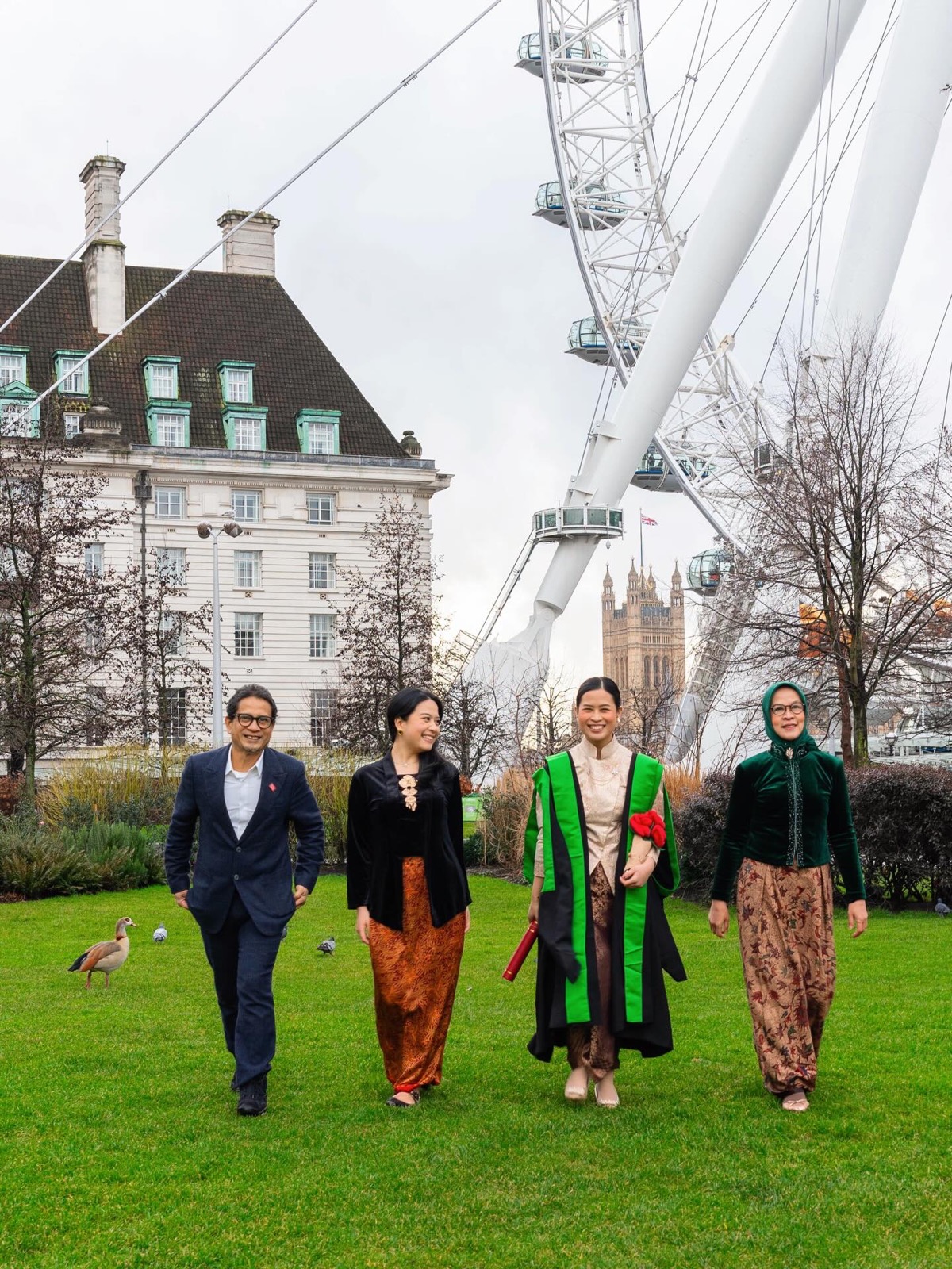 Graduate walking with family near the London Eye in traditional Indonesian dress