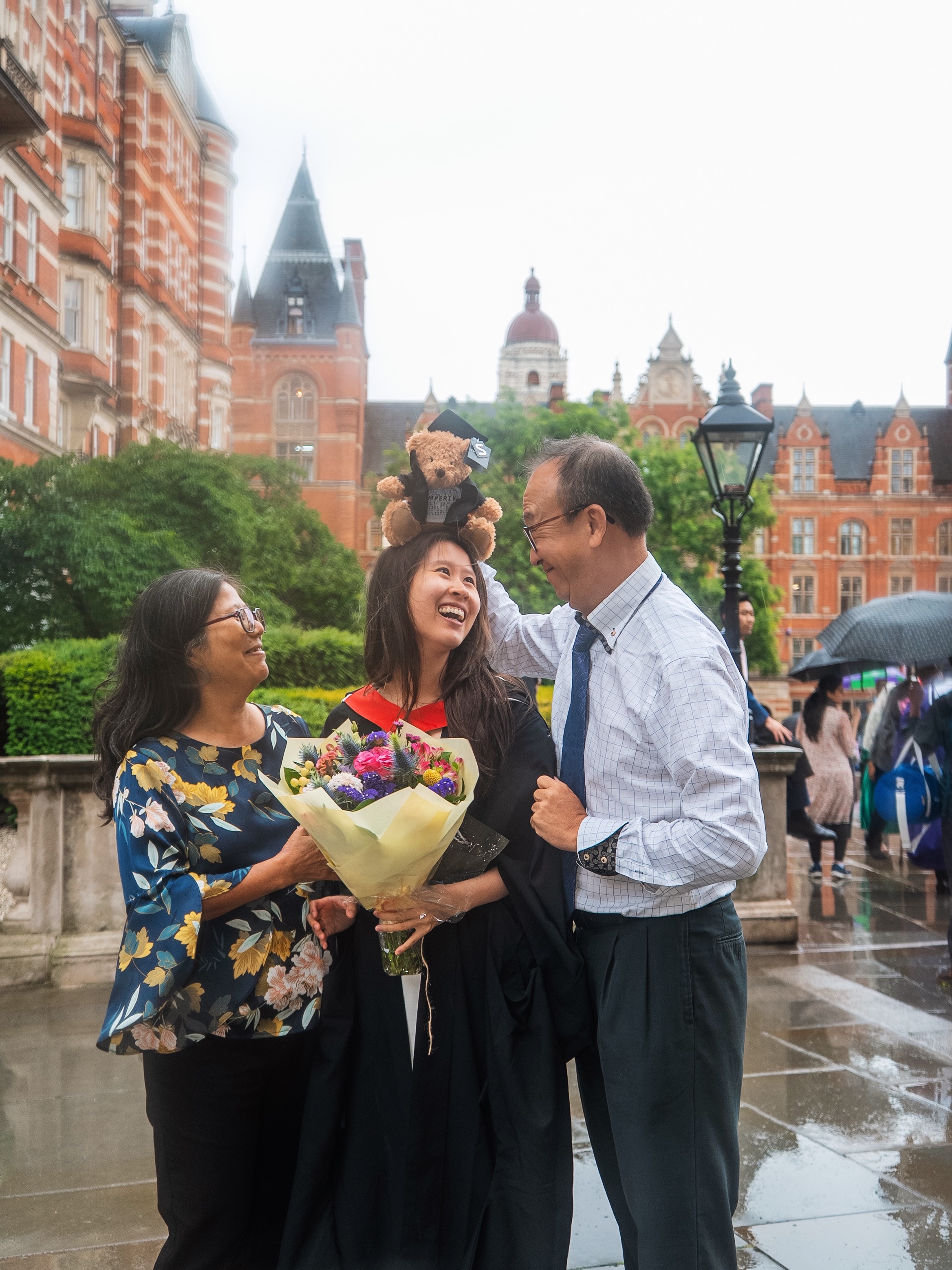 Graduate with family and a graduation teddy bear near Imperial College London
